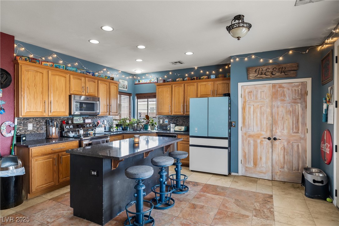 1131 South Blagg Road Pahrump, NV 89048 - Photo 10 of 30 Kitchen featuring visible vents, tasteful backsplash, appliances with stainless steel finishes, a breakfast bar area, and a center island