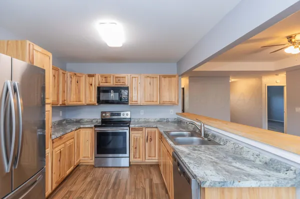 a kitchen with stainless steel appliances granite countertop a refrigerator a stove and a sink