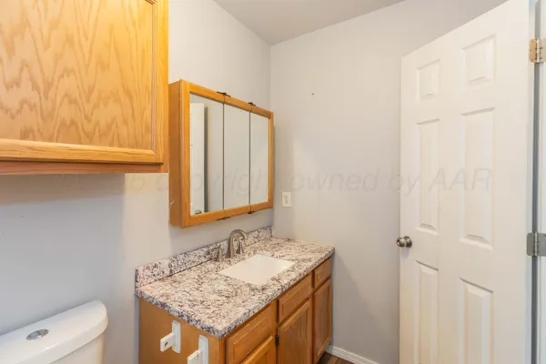 a bathroom with a granite countertop sink and a toilet