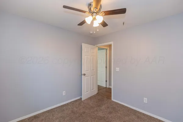 an empty room with a chandelier fan and windows