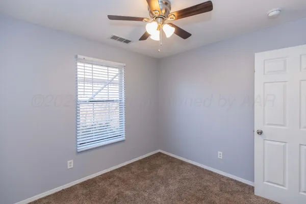 an empty room with windows and fan