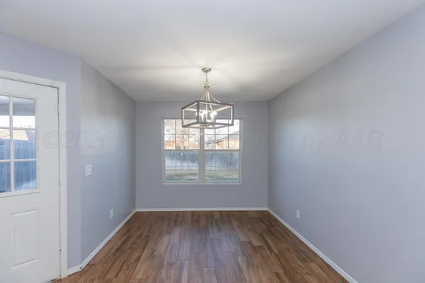 an empty room with wooden floor chandelier and windows