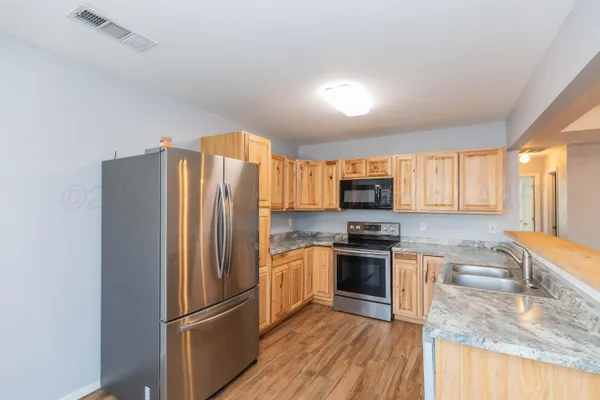 a kitchen with stainless steel appliances granite countertop a refrigerator stove and sink
