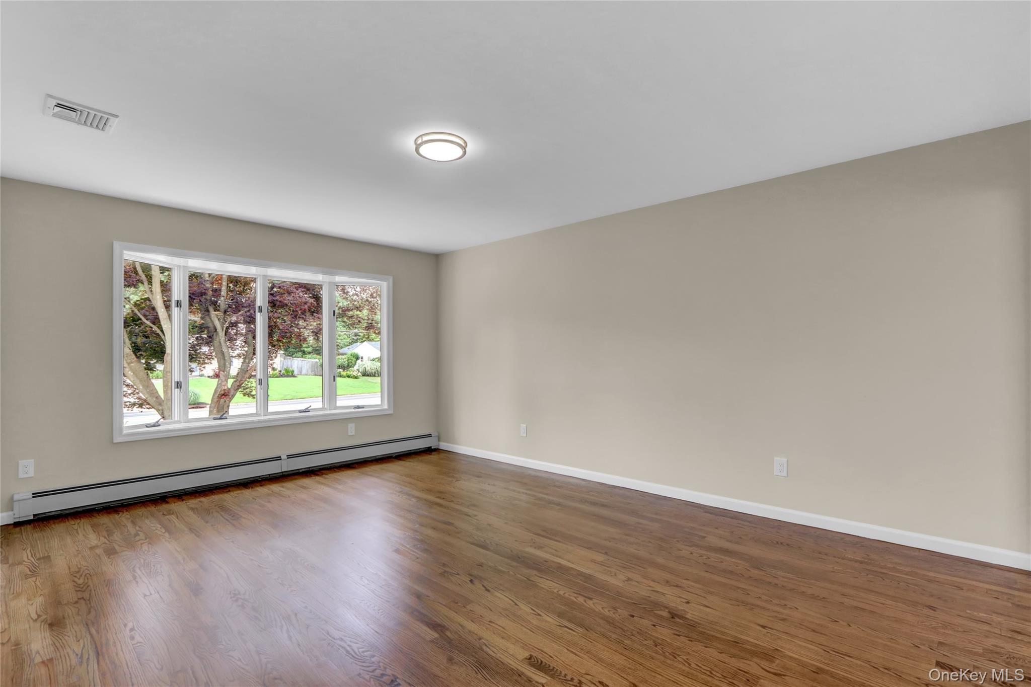 181 Wading River Hollow Road Ridge, NY 11961 - Photo 4 of 24 an empty room with wooden floor and windows