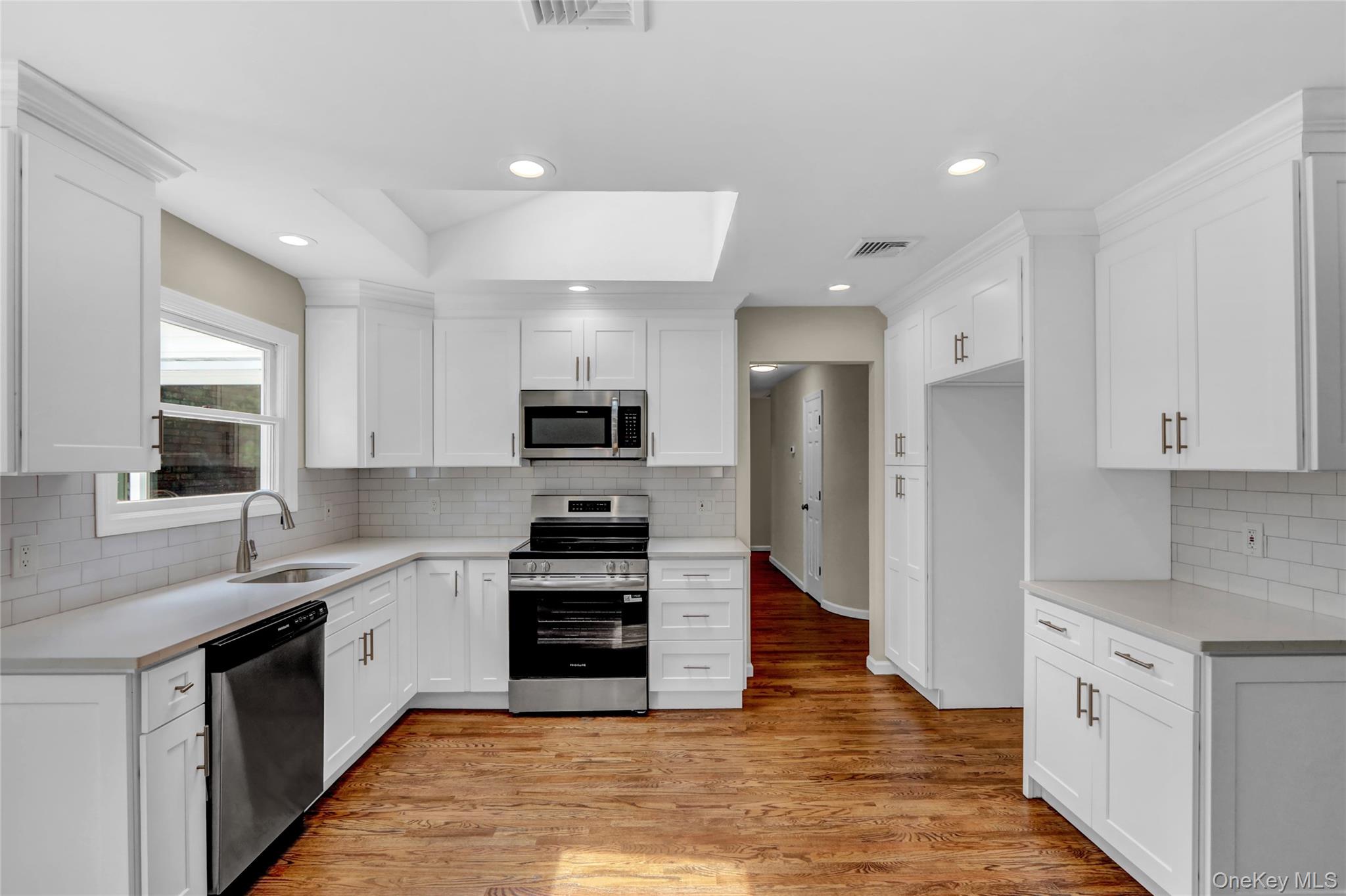 181 Wading River Hollow Road Ridge, NY 11961 - Photo 8 of 24 a large kitchen with stainless steel appliances granite countertop a stove top oven a sink dishwasher and a refrigerator with wooden floor