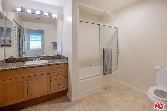 a bathroom with a granite countertop sink mirror and toilet