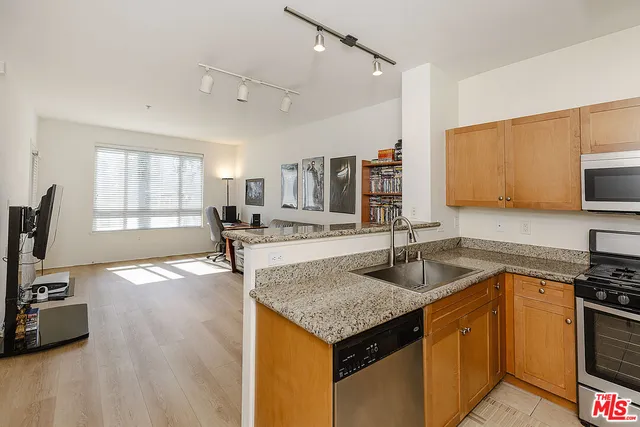 a kitchen with granite countertop a sink a counter top space appliances and cabinets