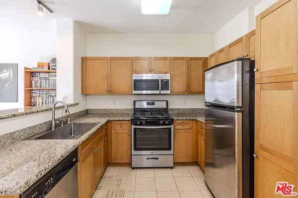 a kitchen with granite countertop a refrigerator stove and microwave