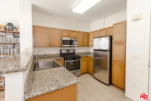 a kitchen with granite countertop a sink a counter top space and stainless steel appliances