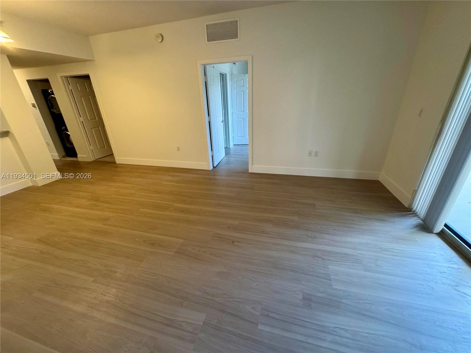 8430 Southwest 8th Street, Unit 201B Miami, FL 33144 - Photo 2 of 14 a view of an empty room with wooden floor and a window