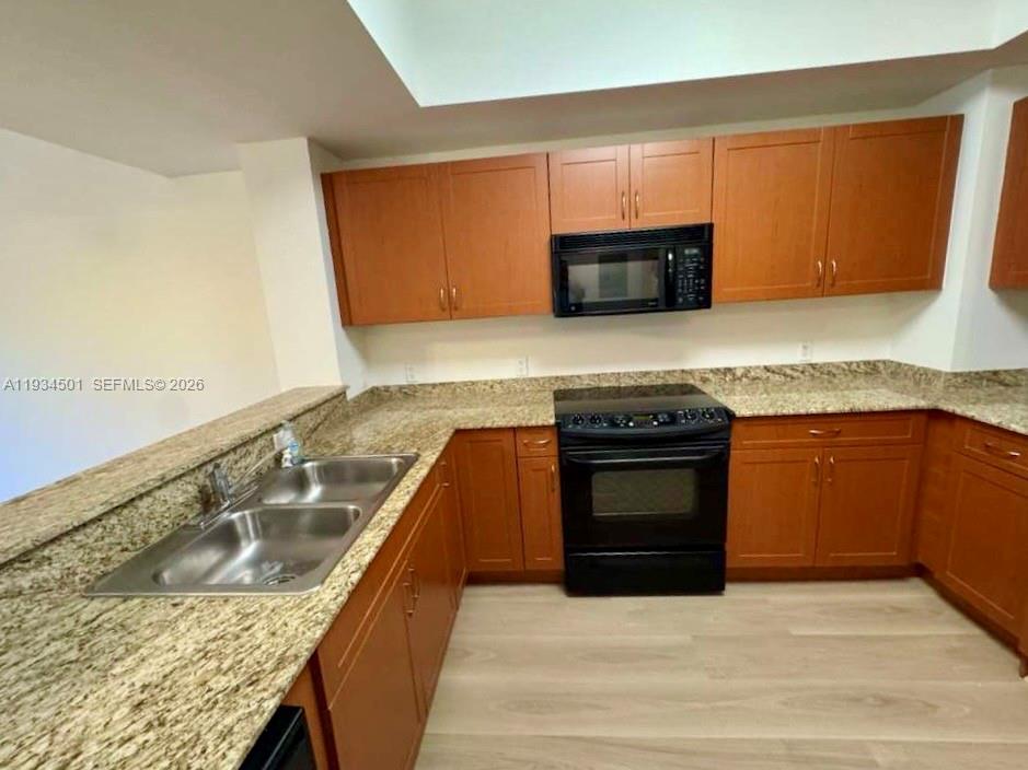 8430 Southwest 8th Street, Unit 201B Miami, FL 33144 - Photo 4 of 14 a kitchen with granite countertop a sink and a stove top oven
