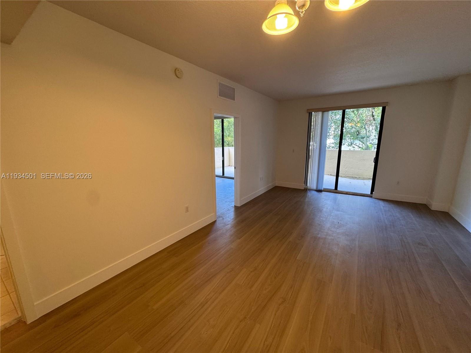 8430 Southwest 8th Street, Unit 201B Miami, FL 33144 - Photo 6 of 14 a view of an empty room with wooden floor and a window
