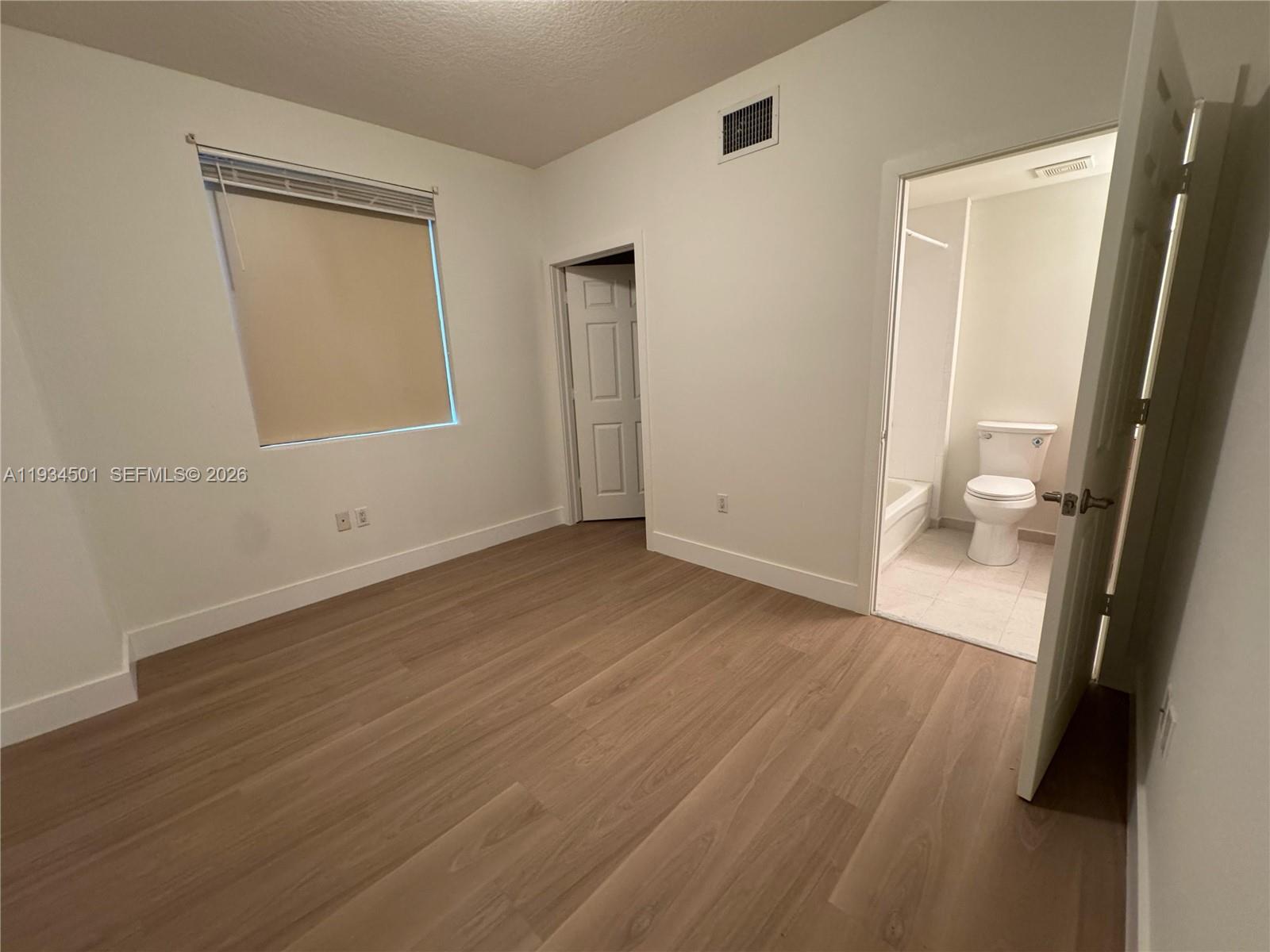 8430 Southwest 8th Street, Unit 201B Miami, FL 33144 - Photo 8 of 14 an empty room with wooden floor and a window