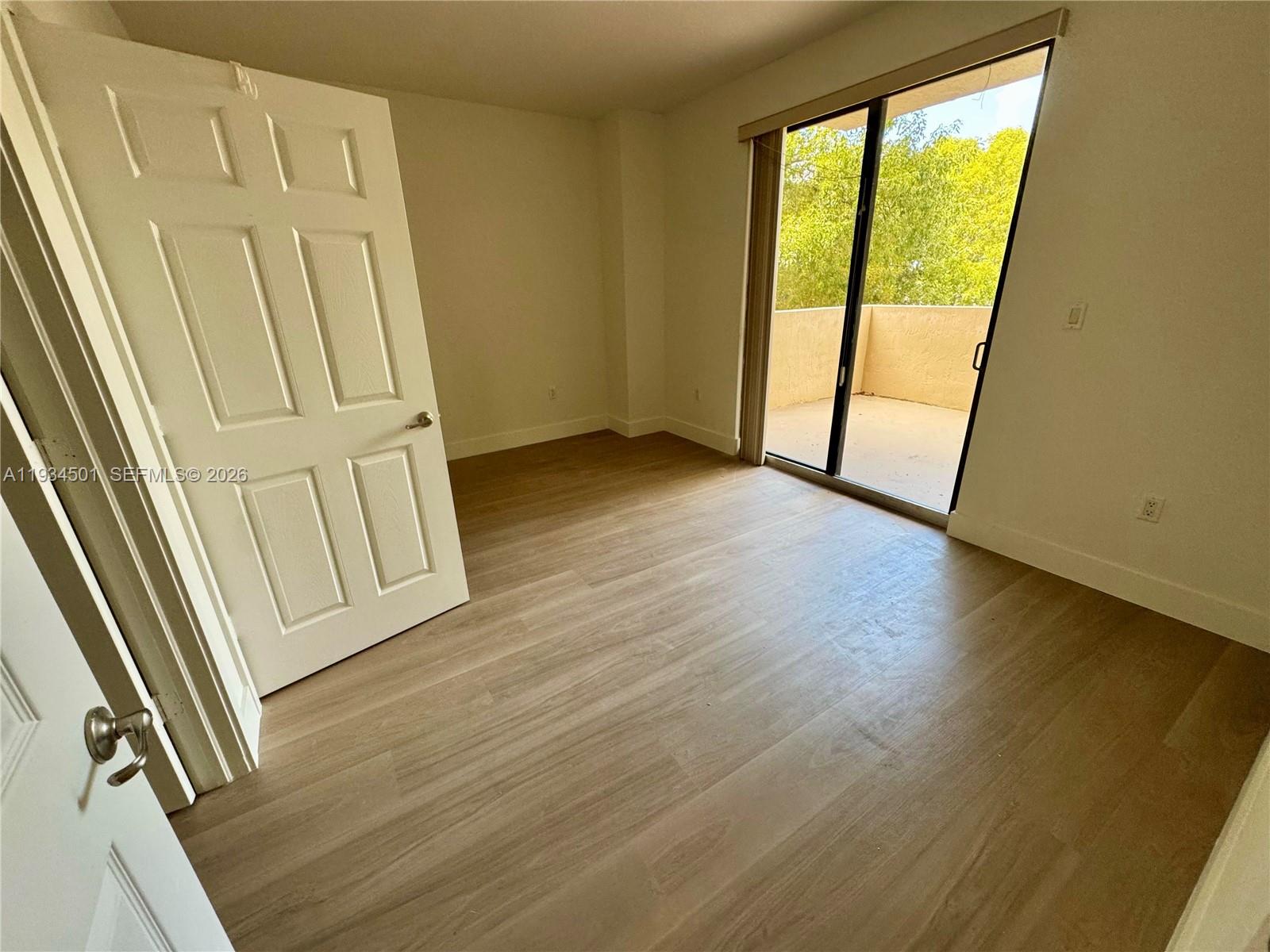 8430 Southwest 8th Street, Unit 201B Miami, FL 33144 - Photo 9 of 14 an empty room with wooden floor and windows