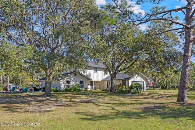 a front view of a house with a big yard and large trees