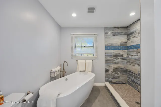 a bathroom with a granite countertop bathtub sink vanity mirror and toilet