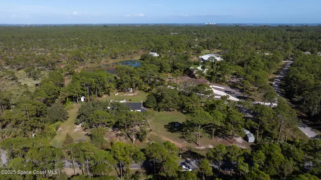 an aerial view of residential houses with outdoor space and trees