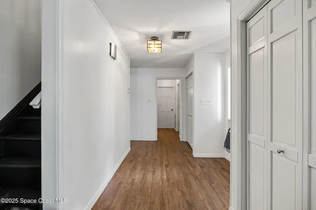 a view of a hallway with wooden floor and staircase