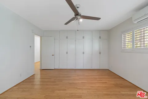 a view of a room with wooden floor and a ceiling fan