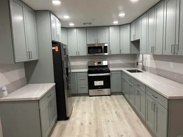 a kitchen with a sink a counter top space stainless steel appliances and cabinets