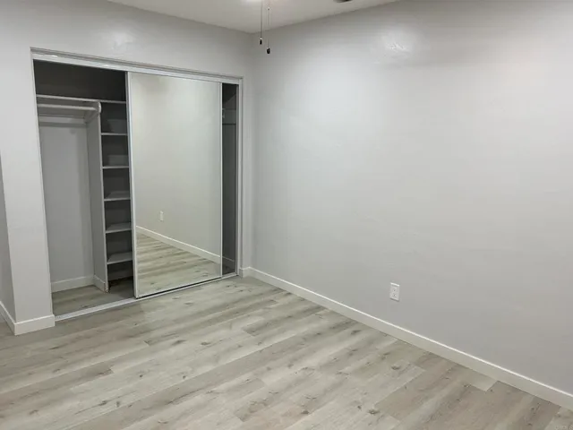 an empty room with wooden floor & closet area