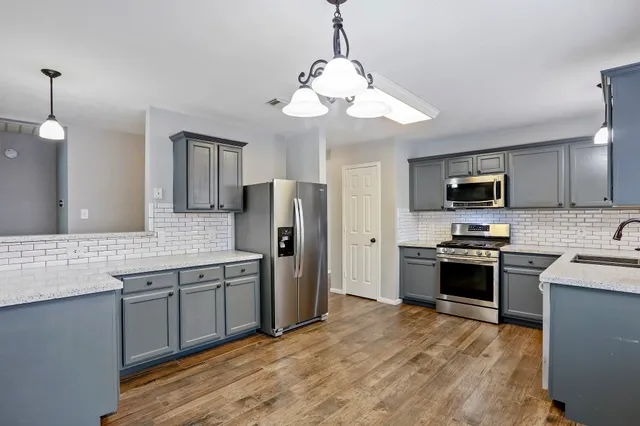 a kitchen with stainless steel appliances granite countertop a refrigerator a stove top oven a sink and dishwasher