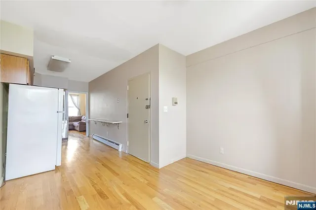 a view of a livingroom with wooden floor and a refrigerator