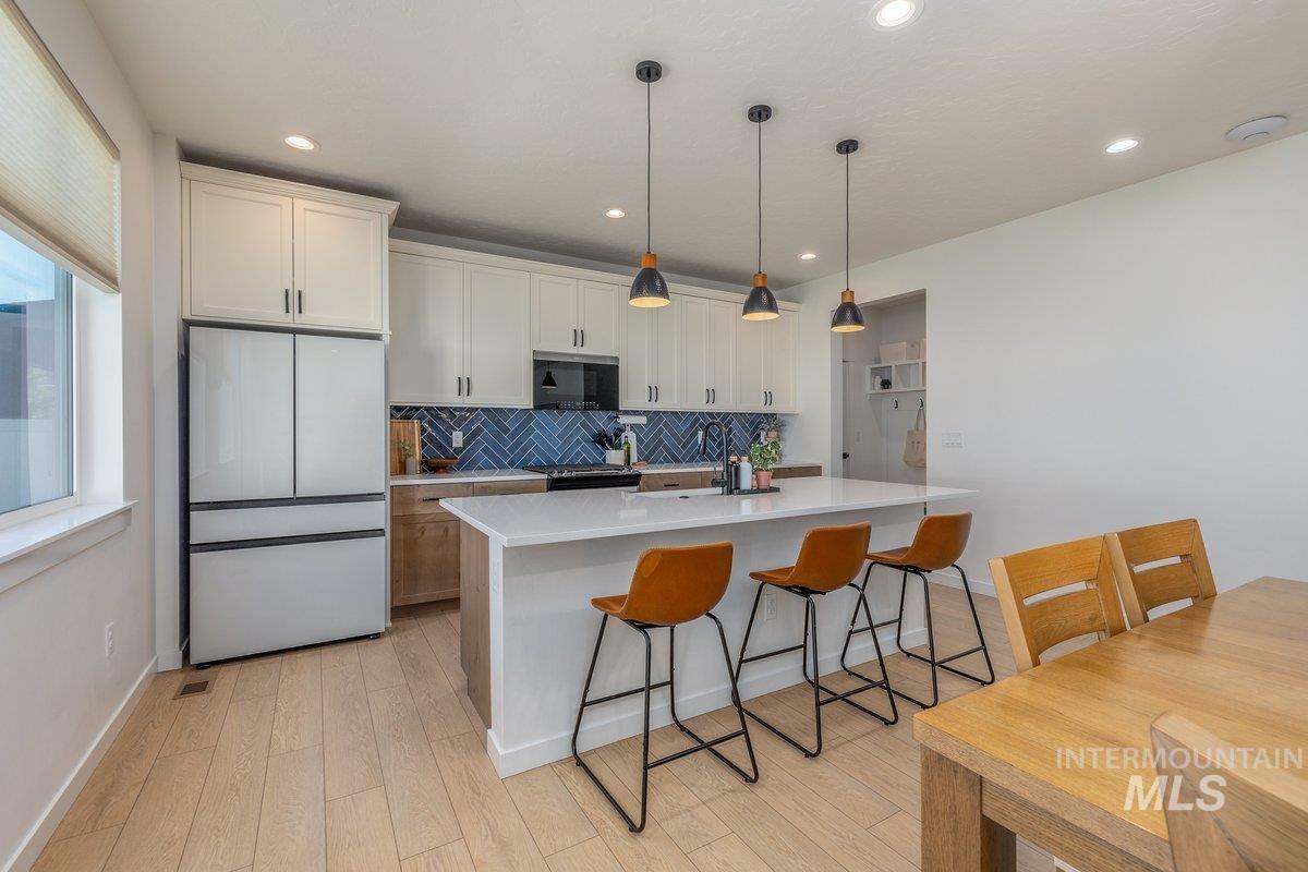 1380 West Chilitna Street Meridian, ID 83642 - Photo 7 of 50 Kitchen featuring a large island with white countertop, pendant lighting, wood-finish flooring, and a blue herringbone tile backsplash