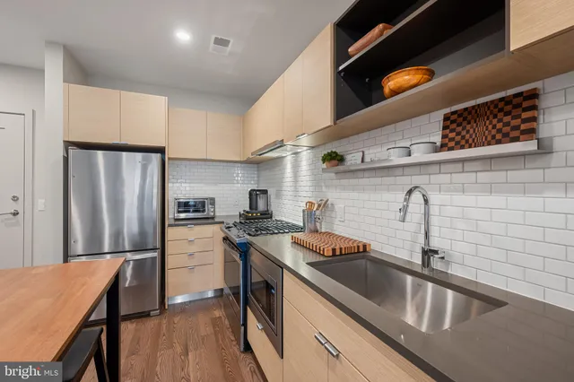 a kitchen that has a sink stainless steel appliances a counter top space and cabinets