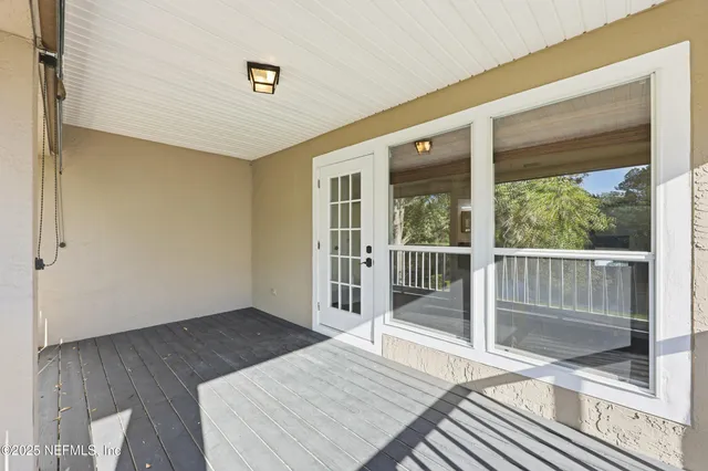 a view of a patio with table and chairs potted plants and floor to ceiling window