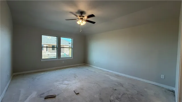 en empty room with windows and chandelier fan