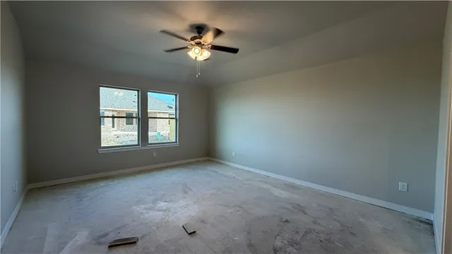 an empty room with a chandelier fan and a window