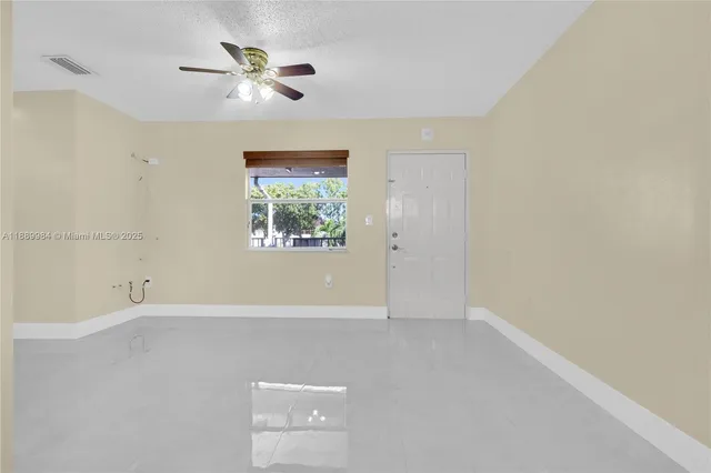 an empty room with a ceiling fan and window