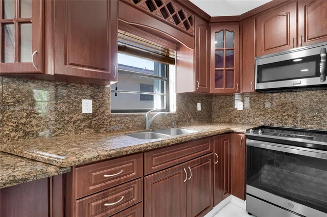 a kitchen with stainless steel appliances granite countertop a refrigerator a stove and a sink with wooden floor