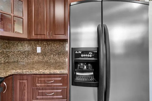 a kitchen with a refrigerator and chairs