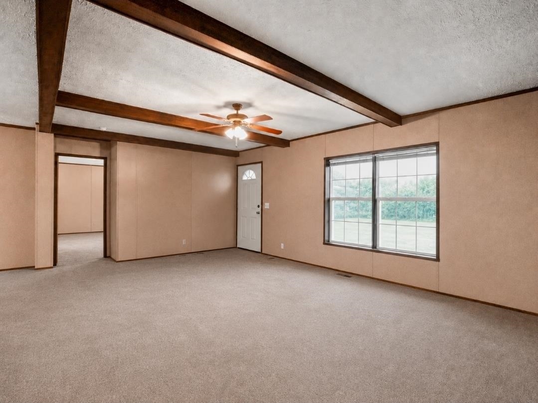 3779 Dancyville Road Stanton, TN 38069 - Photo 13 of 22 Spacious room with a light-toned carpet, exposed ceiling beams, and a ceiling fan
