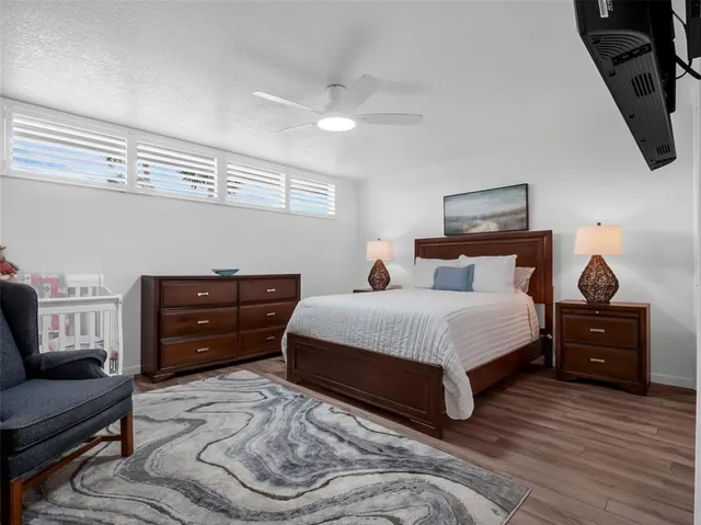 a bedroom with a bed a desk and chair with wooden floor