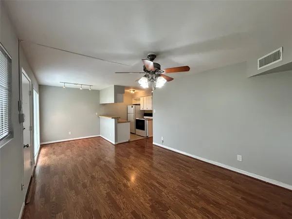 a view of a kitchen with wooden floor a ceiling fan and a window