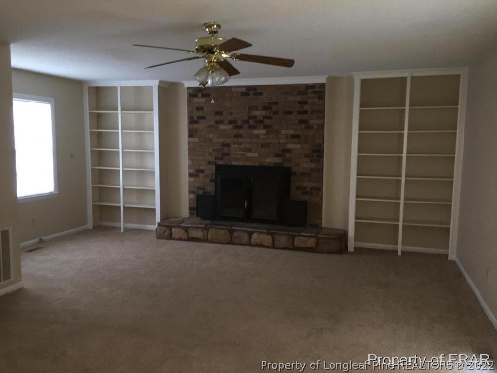 1413 Hibiscus Road Fayetteville, NC 28311 - Photo 5 of 10 an empty room with a fireplace and window
