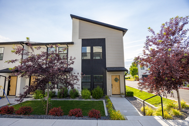 220 Spring Creek Parkway Providence, UT 84332 - Photo 5 of 26 Modern exterior with contrasting light and dark siding, a natural wood-finish front door, and a striking asymmetrical roofline