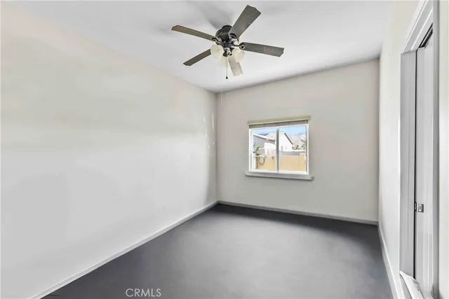 an empty room with a window and a ceiling fan