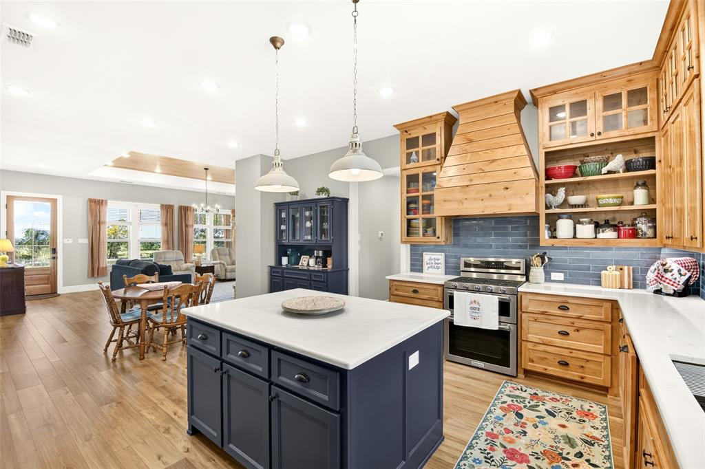 10828 Gregory Road Sanger, TX 76266 - Photo 11 of 37 Kitchen featuring a contrasting island with a white countertop, natural wood cabinetry, stainless steel appliances, blue subway tile backsplash, and wood-finish flooring