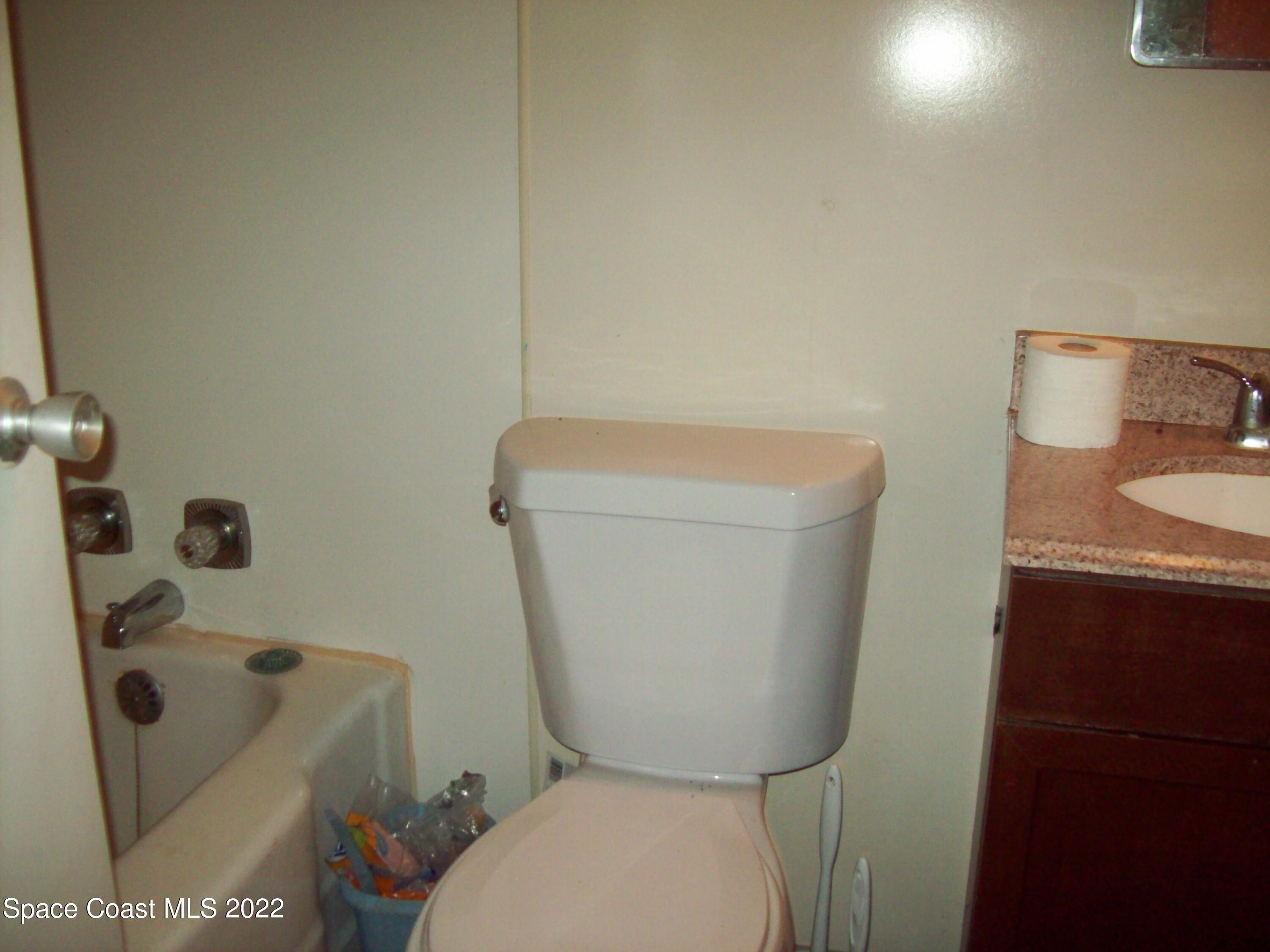2224 Iowa Street Melbourne, FL 32904 - Photo 14 of 19 a white toilet sitting next to a sink and a vanity
