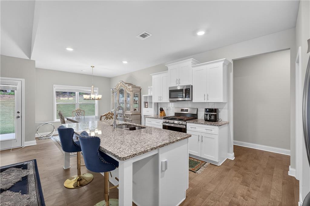 8325 Loch Lomand Lane Winston, GA 30187 - Photo 18 of 31 a kitchen with stainless steel appliances granite countertop a stove top oven a sink dishwasher and white cabinets with wooden floor