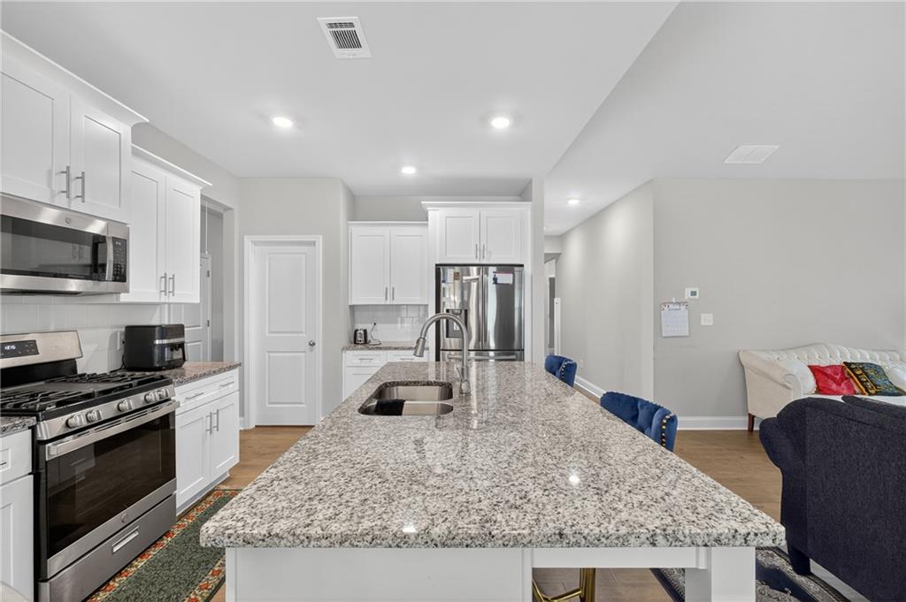 8325 Loch Lomand Lane Winston, GA 30187 - Photo 19 of 31 a kitchen with stainless steel appliances granite countertop a stove top oven a sink and cabinets