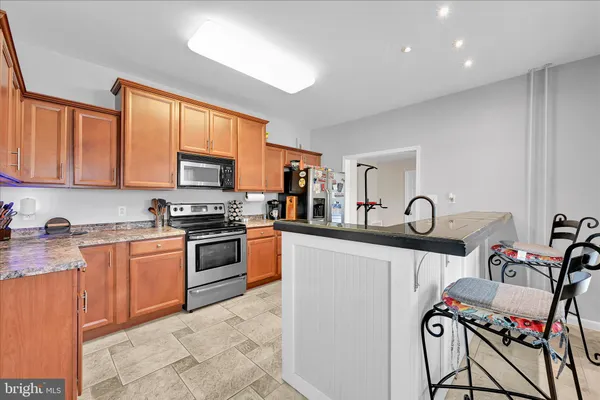 a kitchen with granite countertop stainless steel appliances a sink stove refrigerator and cabinets