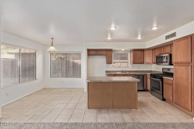 a kitchen with stainless steel appliances granite countertop a stove top oven a sink dishwasher a refrigerator and white cabinets with wooden floor