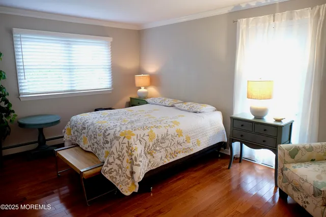 a bedroom with a bed a dresser with wooden floor