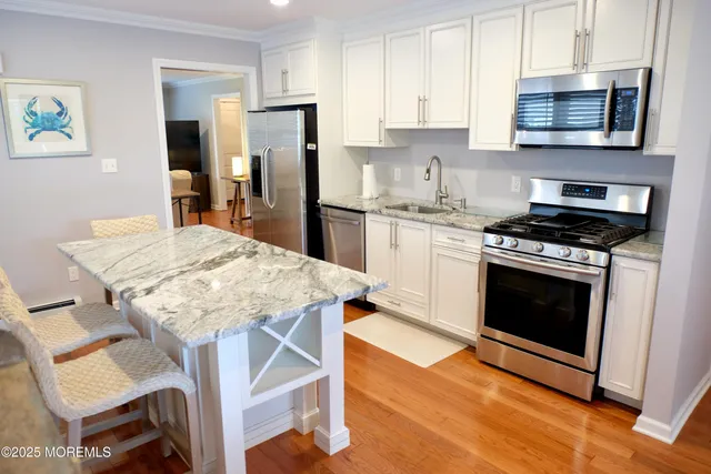 a kitchen with stainless steel appliances a stove a sink dishwasher a refrigerator with a dining table and chairs