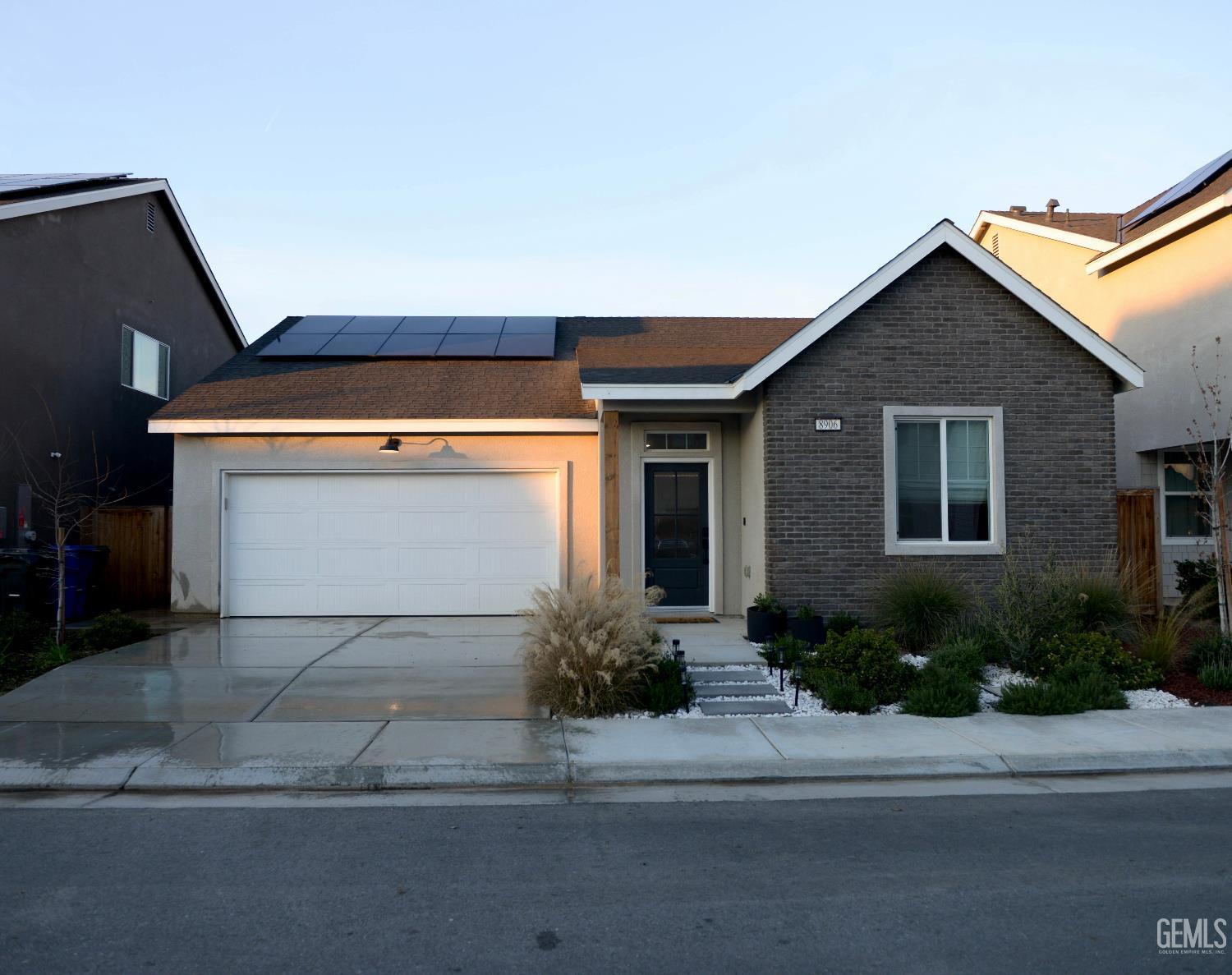 a front view of a house with garage and plants